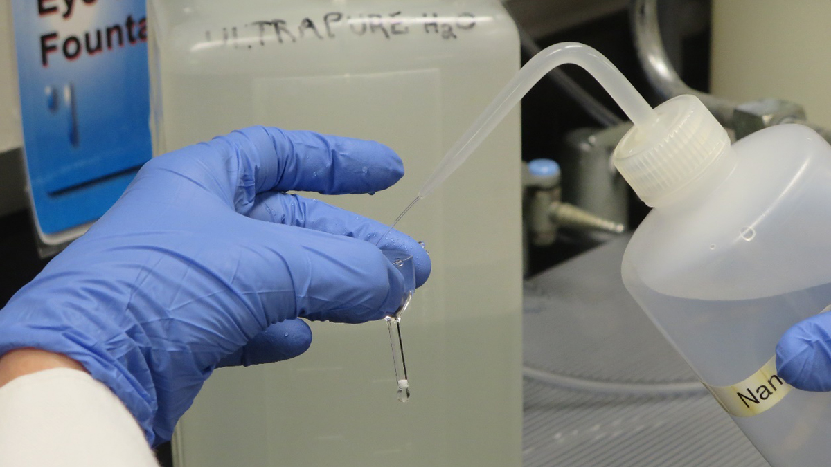 researcher filling a vial with clear liquid